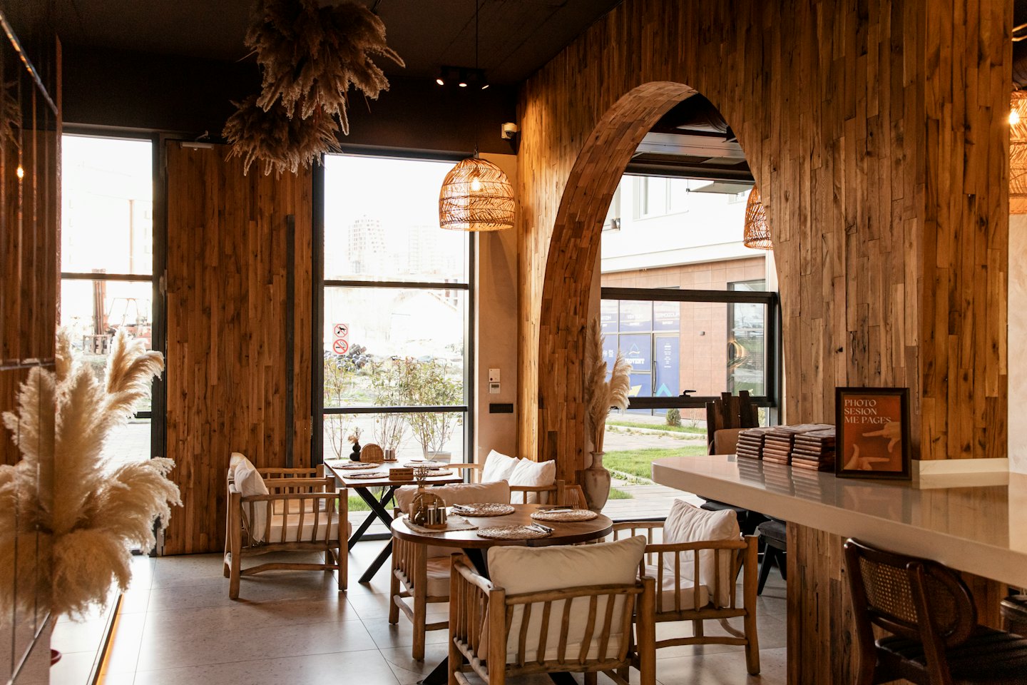 Leerer Café-Innenraum mit Holztischen und Torbogen.