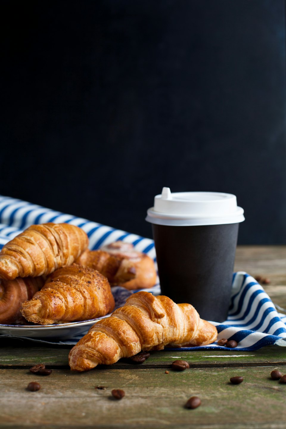 Goldene Croissants und Zimtschnecken auf einem rustikalen Holztisch.