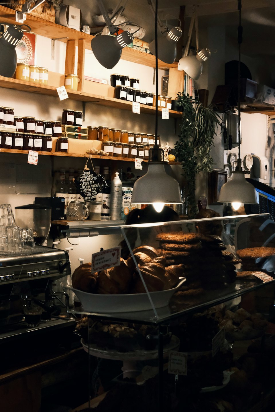Café-Theke mit Gebäck, Marmeladengläsern und Espressomaschine.